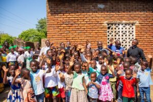 Children from Katelera zone in the Archdiocese of Lilongwe pose for a photo with Daria from the Archdiocese of Boston, USA