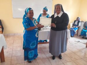 Teresian Sisters mother Superior General, Sr Colleta Bester, presenting a certificate to one of the trainees from Dzaleka Refugees camp