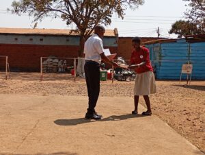 Mr Chikafa gives a certificate to Naomi after completing her Computer training