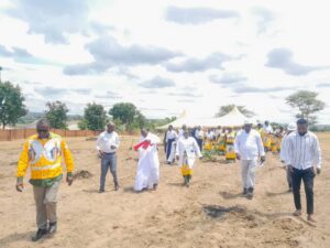 Mumba leading the team to a construction site where the Priest house will be built
